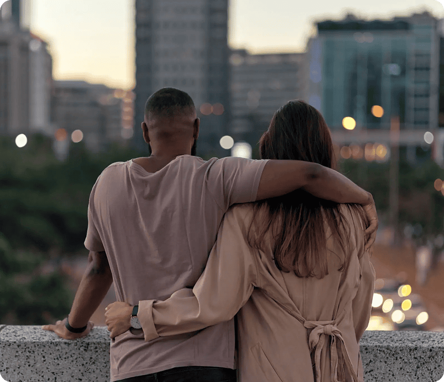 Couple embracing with city skyline view.