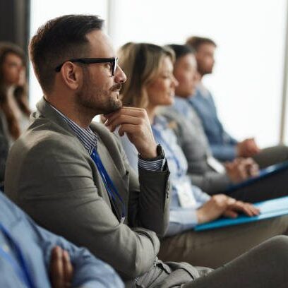 Profile view of smiling businessman and group of his colleagues attending a seminar in board room.